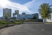 a city street surrounded by grass and tall buildings at the end of a street there is a paved pathway in front of the building