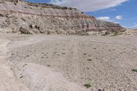 a lone yellow and gray van parked on the side of a rocky road in front of a large rock formation