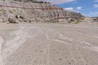 a lone yellow and gray van parked on the side of a rocky road in front of a large rock formation