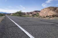 a bicycle rider is stopped on a long empty road in the desert near mountains and mountains