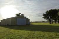 two large grain bins sit in the center of a field, surrounded by silos