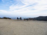 there are two people riding horses in the dirt area of a field in the mountain