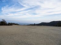 there are two people riding horses in the dirt area of a field in the mountain