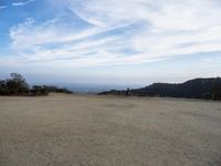 there are two people riding horses in the dirt area of a field in the mountain