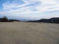 there are two people riding horses in the dirt area of a field in the mountain