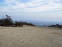 there are two people riding horses in the dirt area of a field in the mountain