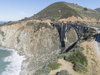 a view of the ocean as a train travels over the bridge over a cliffside