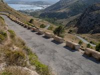 three cement barricades are placed on the road and along the side of the mountains