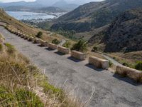 three cement barricades are placed on the road and along the side of the mountains