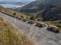 three cement barricades are placed on the road and along the side of the mountains