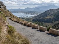 three cement barricades are placed on the road and along the side of the mountains