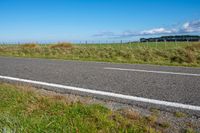 road sign on a country roadway with sea behind it and grassy field in the foreground