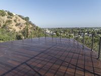 a deck with water pouring in and railing along the bottom of it and below a hillside