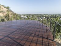 a deck with water pouring in and railing along the bottom of it and below a hillside