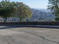 a red fire hydrant standing on a street with hills in the background and blue sky