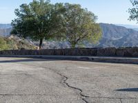 a red fire hydrant standing on a street with hills in the background and blue sky