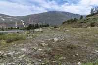 there is a small lake on the side of the mountain and there is a snow capped mountain in the distance