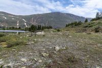 there is a small lake on the side of the mountain and there is a snow capped mountain in the distance