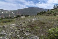 there is a small lake on the side of the mountain and there is a snow capped mountain in the distance