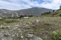 there is a small lake on the side of the mountain and there is a snow capped mountain in the distance