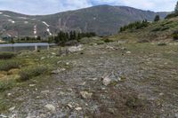 there is a small lake on the side of the mountain and there is a snow capped mountain in the distance