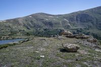 mountains are covered with green grass and rocks with snow on the slopes in the distance