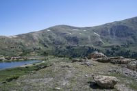 mountains are covered with green grass and rocks with snow on the slopes in the distance