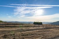 dirt road leading to a pasture with mountains in the distance near an empty field of grass