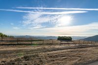 dirt road leading to a pasture with mountains in the distance near an empty field of grass