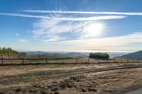 dirt road leading to a pasture with mountains in the distance near an empty field of grass