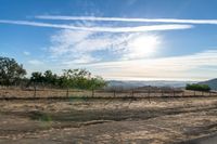 dirt road leading to a pasture with mountains in the distance near an empty field of grass