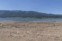 mountains and lake in a desert field with brown dirt and grass in front of water