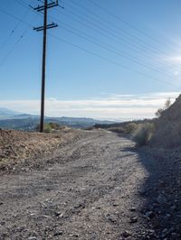 a mountain road with an old telephone tower in the background and dirt road on either side