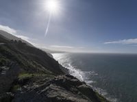 a beautiful view with sun flare over the ocean from the cliff on top of a hill