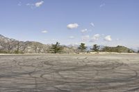 a view along a dirt road of an empty field and mountains in the distance of the scene