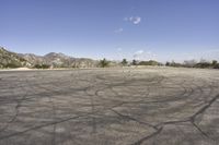 a view along a dirt road of an empty field and mountains in the distance of the scene