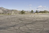 a view along a dirt road of an empty field and mountains in the distance of the scene