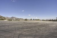 a view along a dirt road of an empty field and mountains in the distance of the scene