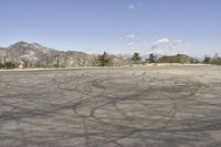 a view along a dirt road of an empty field and mountains in the distance of the scene