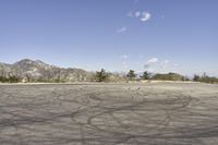 a view along a dirt road of an empty field and mountains in the distance of the scene