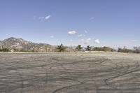 a view along a dirt road of an empty field and mountains in the distance of the scene