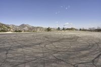 a view along a dirt road of an empty field and mountains in the distance of the scene