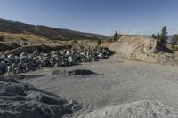 there is a bike rider on a paved dirt road through rocky area near a mountain