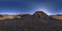 a scenic view of a rocky area, mountains and a river below a clear sky