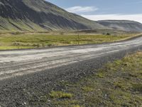 the motorcycle is going down the road in a mountainous area with hills in the background