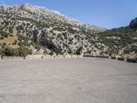 a building that is standing in the middle of the street with a rocky hill behind it