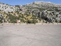 a building that is standing in the middle of the street with a rocky hill behind it