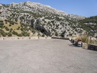 a building that is standing in the middle of the street with a rocky hill behind it