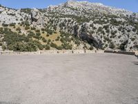 a building that is standing in the middle of the street with a rocky hill behind it