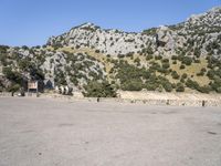 a building that is standing in the middle of the street with a rocky hill behind it